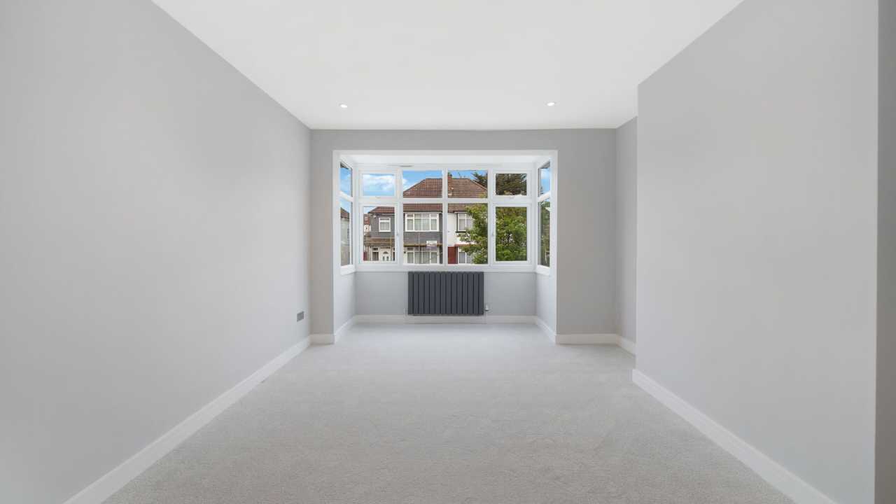Spacious living room with bay window and modern radiator in Harrow property for sale.
